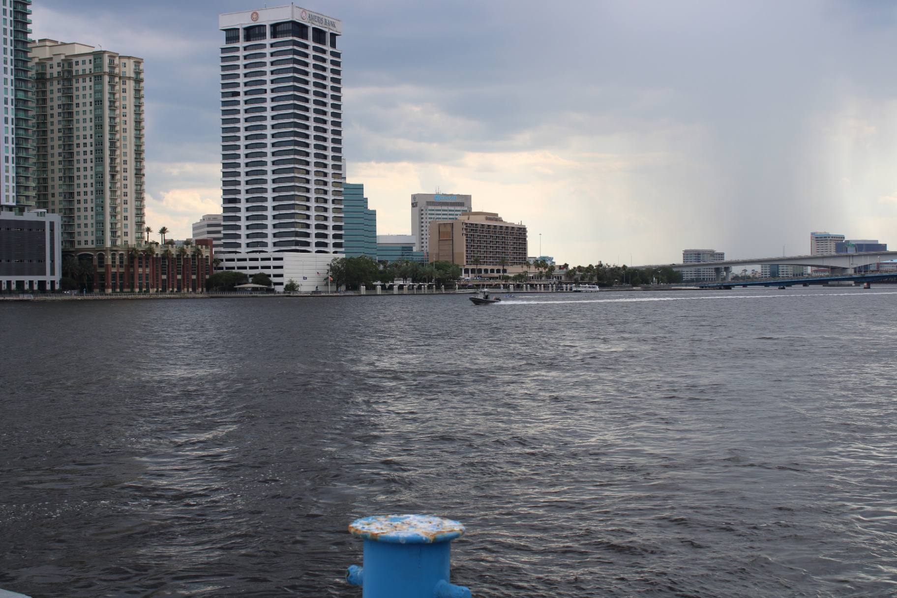 Downtown Jacksonville skyline along the St. Johns River with a small boat passing by, viewed from the pier