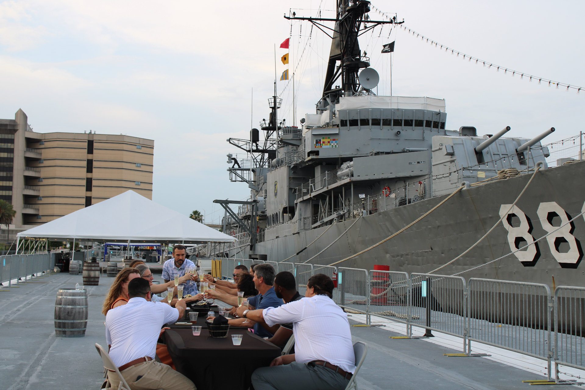 Guests raising a champagne toast at the dinner table beside the USS Orleck destroyer 886